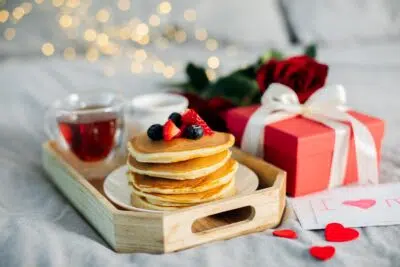 Mother's Morning breakfast on wooden tray with greeting card I love you mom, bouquqet of red roses