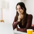 Portrait of young adult student sitting on table using laptop learning online