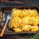 Potato casserole Gratin Dauphinois in a baking dish. Dark wooden background. Top View