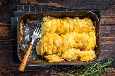 Potato casserole Gratin Dauphinois in a baking dish. Dark wooden background. Top View