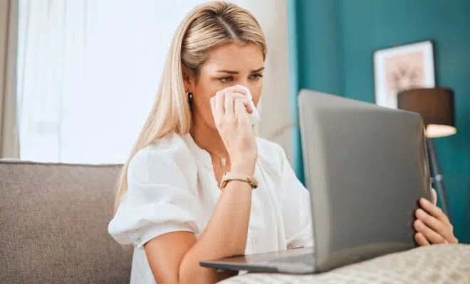 Sad, crying and laptop with woman on sofa for depression, mental health and lonely from message not