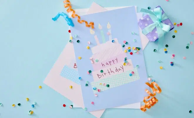 top view of colorful confetti near birthday greeting cards on blue background