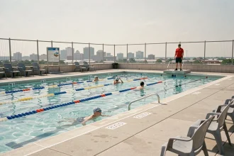 Piscine municipale extérieure avec couloirs de nage, maître-nageur en poste et nageurs adultes par une journée estivale